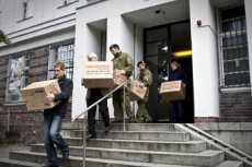 Полицейские выносят документы, изъятые в ходе обыска в клиниках немецкого Красного Креста.